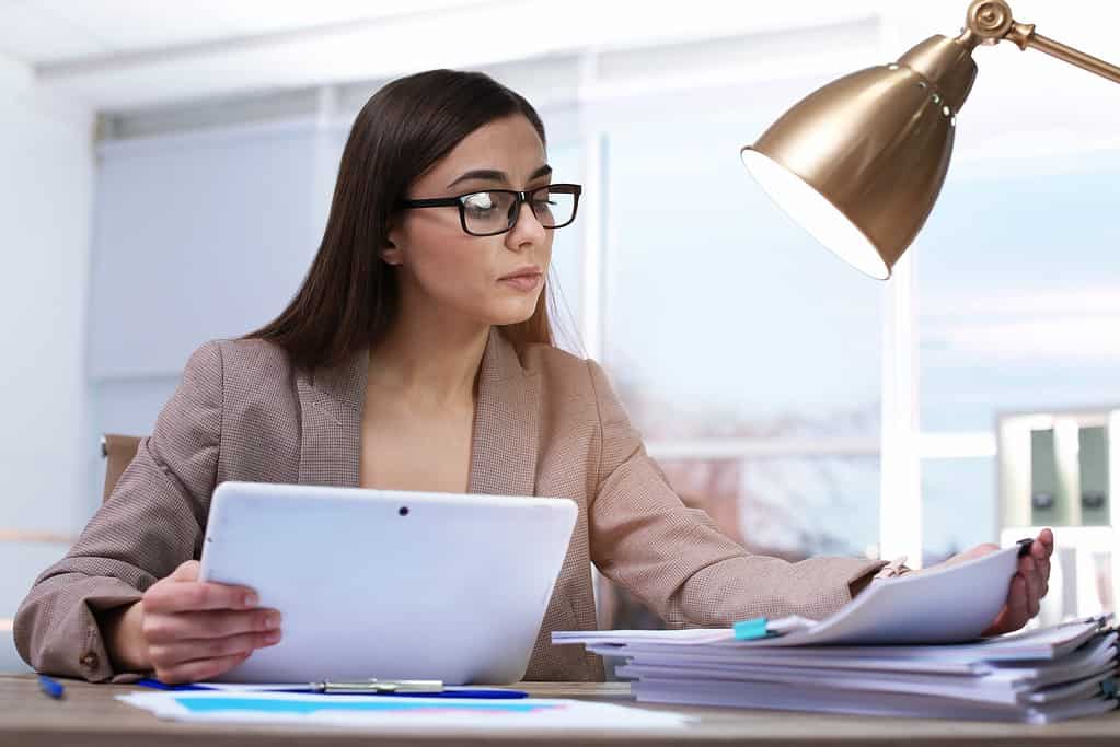 Businesswoman working with tablet and documents at table in office