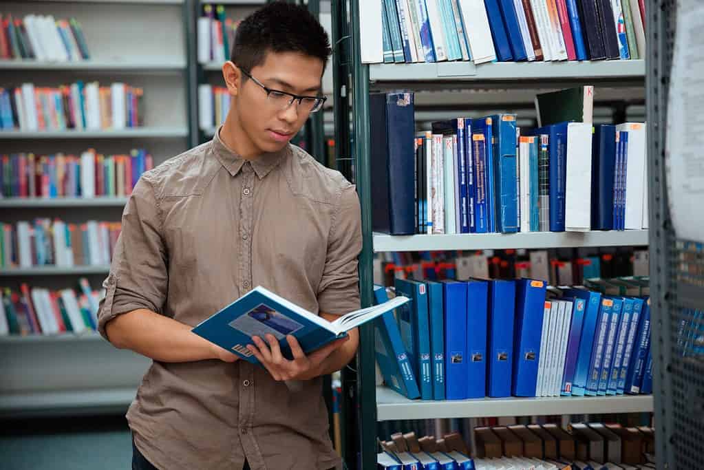 Portrait of asian student reading book in library